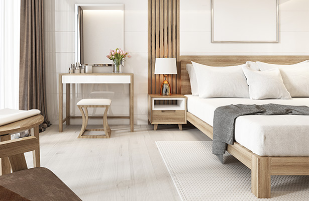 modernes Schlafzimmer in Hellbraun und weiß gehalten. Holzbett mit weißen Bezügen sowie Nachttisch und Schminktisch aus Holz.