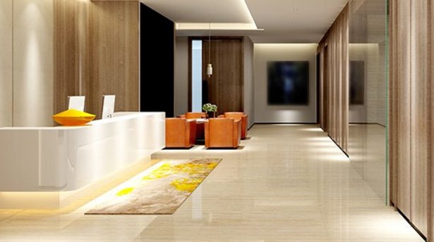 Eine Hotellobby mit orangenen Sesseln, sehr modern eingerichtet mit hohen Decken und braun-weißer Innenausstattung. 