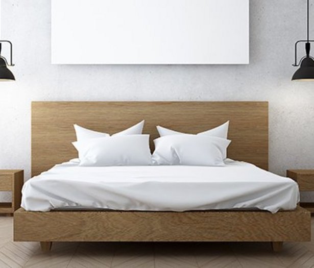 Ein hellbraunes Doppelbett mit weißen Bettbezügen und  schwarze Dekolampen.